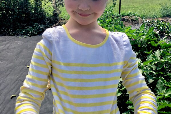 young girl holds cherry tomatoes in her shirt