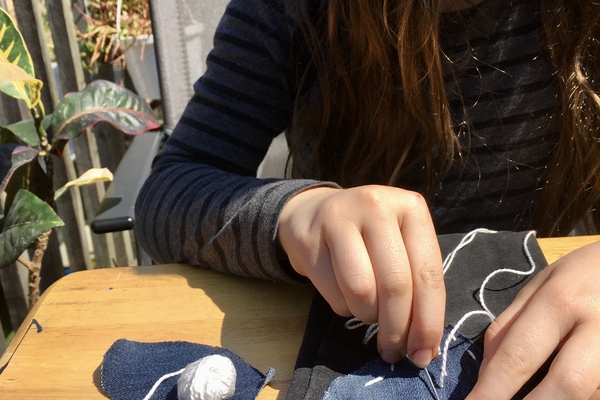 child sews heart patches.