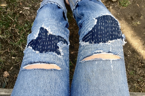 overhead view on jeans with hand mended patches.