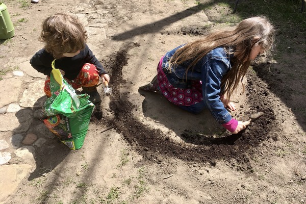 two small children dig a semi circle in the dirt